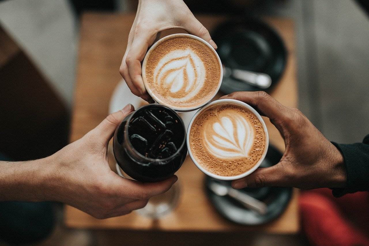 3 hands toast each other with 3 cups of coffee